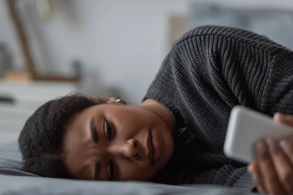 Mulher Multirracial Deprimida Usando Telefone Celular Enquanto Deitada Cama Casa — Fotografia de Stock