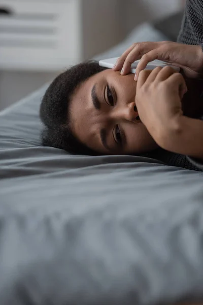 Αναστατωμένη Πολυφυλετική Γυναίκα Μιλάει Στο Smartphone Ενώ Βρίσκεται Στο Κρεβάτι — Φωτογραφία Αρχείου