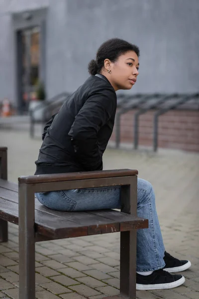 stock image multiracial woman with mental crisis sitting on bench on urban street 