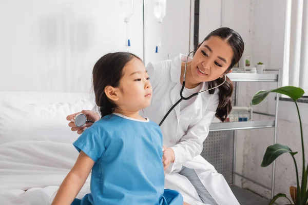 Médico Positivo Com Estetoscópio Examinando Criança Asiática Vestido Hospital Sentado — Fotografia de Stock