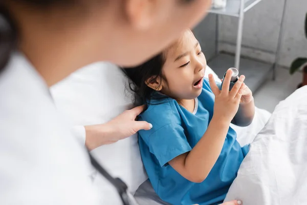 Pediatra Borrosa Tocando Hombro Niño Asiático Usando Inhalador Sala Hospital — Foto de Stock