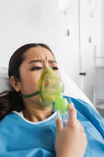 忧心忡忡的亚洲女人躺在诊所床上 戴着氧气面罩呼吸 — 图库照片