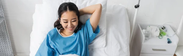 Hastane Önlüklü Genç Asyalı Kadın Yatakta Gülümsüyor Afiş — Stok fotoğraf