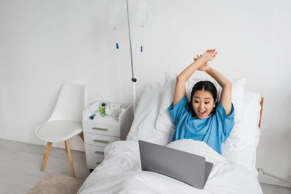 Excited Asian Woman Raised Hands Watching Movie Laptop Hospital Ward — Stock Photo, Image