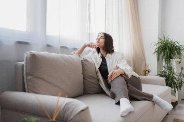 Genç bir kadın evdeki kanepede otururken gözlerini kaçırıyor. 