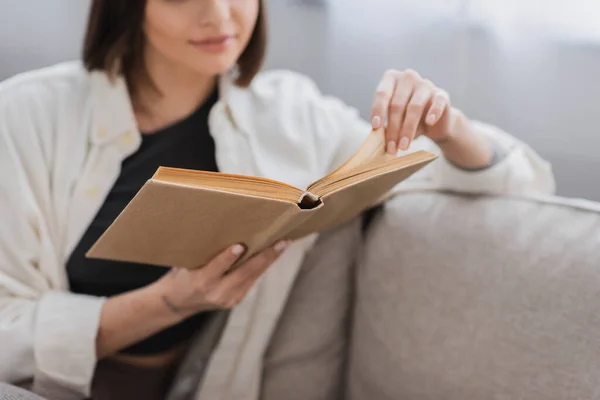 Vista Cortada Livro Leitura Mulher Borrada Enquanto Sentado Sofá Casa — Fotografia de Stock