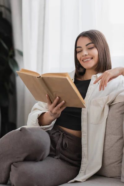 Mulher Positiva Ler Livro Enquanto Descansa Sofá Casa — Fotografia de Stock