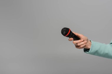 Cropped view of hand of host of event in blue jacket holding black and wireless microphone during holiday while standing isolated on grey   clipart