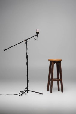 Kahverengi ahşap sandalye siyah mikrofonun yanında duruyor gri arka planda fotokopi alanı, stüdyoda yüksek tabure. 