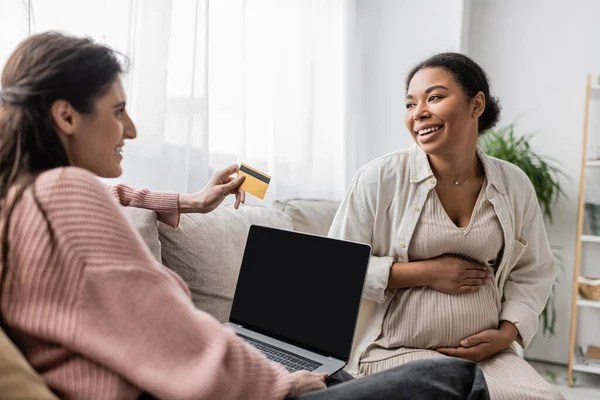 Cheerful Lesbian Woman Looking Pregnant Multiracial Partner While Doing Online — Stock Photo, Image
