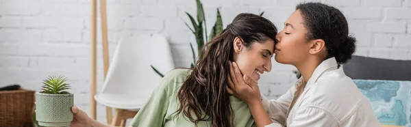 Joyful Multiracial Žena Líbání Čelo Šťastný Přítelkyně Zelenou Rostlinou Prapor — Stock fotografie