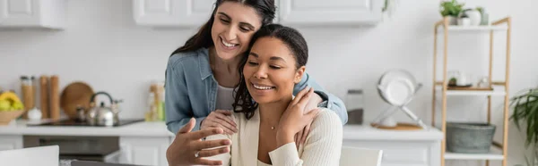 Feliz Interracial Lesbianas Pareja Abrazándose Uno Otro Cocina Bandera — Foto de Stock