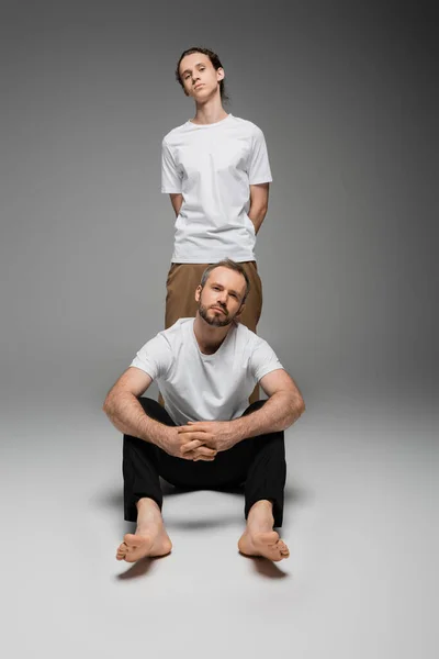 Pełna Długość Brodatego Ojca Nastoletniego Syna Białych Shirtach Pozujących Szaro — Zdjęcie stockowe