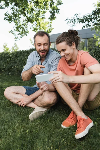 Bearded Father Pointing Finger Smartphone Next Teenage Son Green Park — Stock Photo, Image