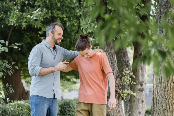 快乐的父亲 留着胡子 抱着快乐的少年儿子在绿地公园里 — 图库照片