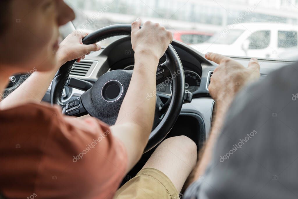 Cropped view of man pointing away with finger while teenage son driving car