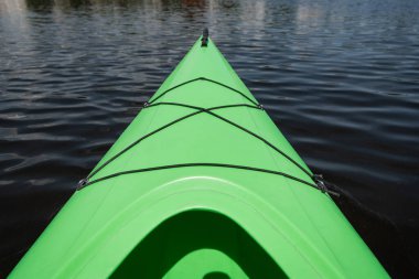 high angle view of front part of bright green sportive kayak on calm water surface in summer, water recreation, vacation destination, summer gateaway, concept clipart