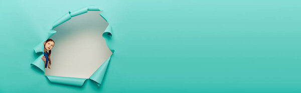 Опасался, что рыжеволосая девочка смотрит в камеру, стоя за дырой в голубой газете и празднуя День защиты детей на белом фоне, баннер 