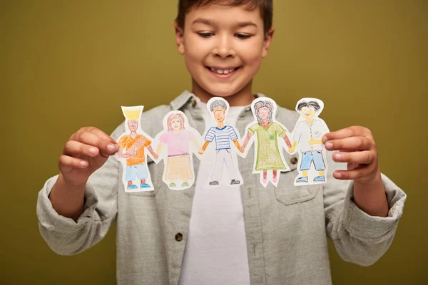 国際的な児童保護の日のお祝いの間に描かれた紙の文字を保持しているぼやけて肯定的な多人種の少年はカーキの背景に — ストック写真