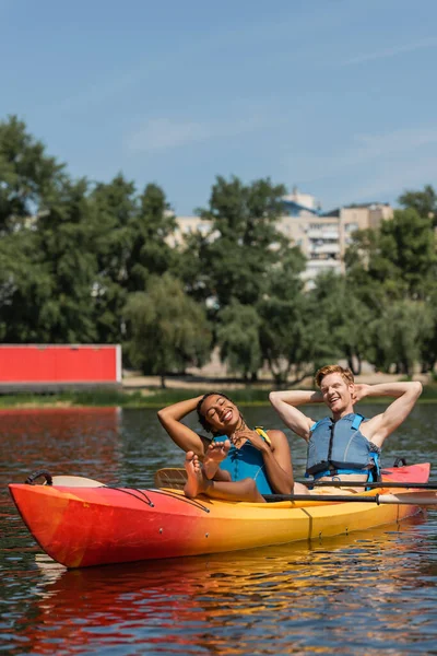 喜んで裸足のアフリカ系アメリカ人女性と笑顔の赤毛の男湖の夏の週末にスポーツカヤックで閉じた目でリラックス — ストック写真