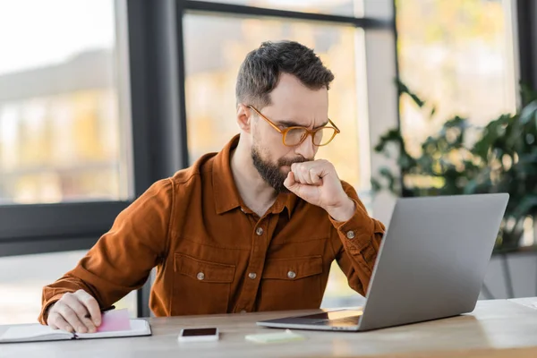Thoughtful Bearded Businessman Eyeglasses Holding Pen Sticky Notes Looking Laptop — Stock Photo, Image