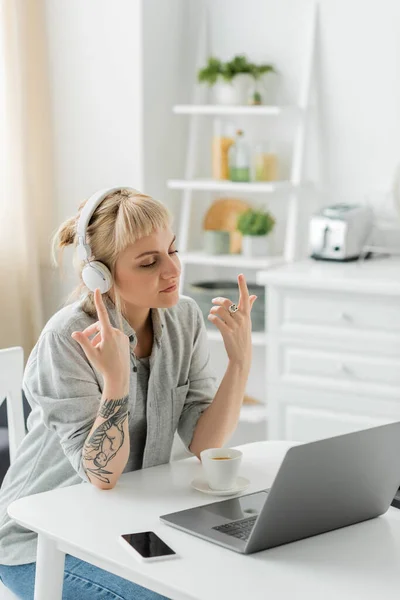 Young Woman Bangs Tattoo Hand Sitting Wireless Headphones Gesturing Laptop — Stock Photo, Image