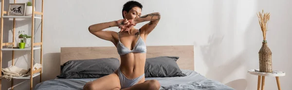 Intriguing Tattooed Woman Silk Lingerie Looking Camera While Posing Grey — Stock Photo, Image