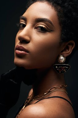 Kendine güvenen, zarif, akşam makyajı ve altın aksesuarları olan Afro-Amerikan kadınının siyah, yüksek moda ve akşam görüntülerine yakından bakın.