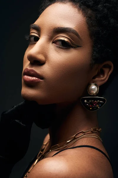 有自信而优雅的年轻非洲裔美国女人的近景 她有着晚妆和金色的配饰 看着被黑色 高级时尚和晚装隔离的相机 — 图库照片