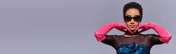 コピースペース 現代世代Zファッションコンセプト バナーとグレーに隔離されたポーズサングラス ピンクの手袋 カクテルドレスでトレンディな若いアフリカ系アメリカ人モデル — ストック写真