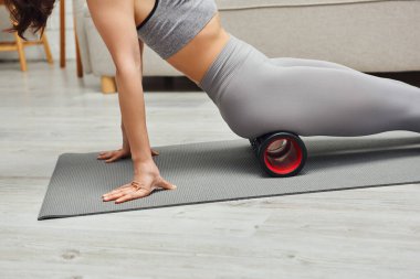 Aktif kıyafetli genç bir kadının salonda lenf tirajı ve spor paspası için tekerlekli sandalyede oturması sağlıklı lenfatik sistem konseptini ve miyofasiyal salınımı koruyor.