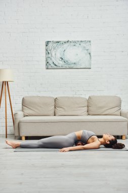 Aktif kıyafetli genç esmer ve çıplak ayaklı bir kadının evdeki fitness minderinde kendine masaj yaparken masaj yapması, lenf akışını ve ev konseptindeki sağlığını teşvik etmesi, gerilimin azaltılması...
