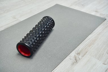 Evdeki spor paspasının üzerine uzanmış modern siyah tekerlekli masaj aleti, ev konseptinde lenf akışı ve sağlığını, güzellik ve sağlık rutinini, sağlık ve rahatlamayı teşvik ediyor. 