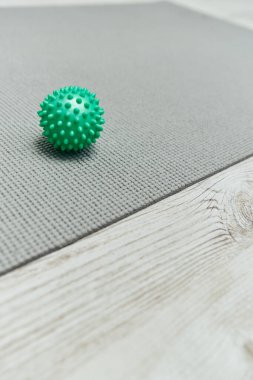 Close up view of handle massage ball lying on fitness mat on floor at home, natural health practices and home-based massage concept, health and relaxation, beauty and wellness routine  clipart