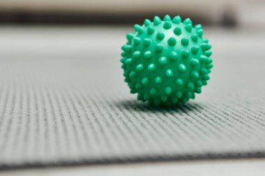 Close up view of handle massage ball on fitness mat on floor at home, natural health practices and home-based massage concept, health and relaxation, beauty and wellness routine  clipart