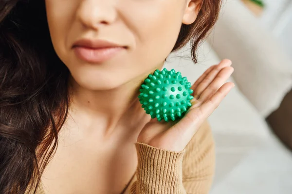 stock image Cropped view of blurred young brunette woman massaging neck with manual massage ball at home, lymphatic system support and home-based massage, balancing energy and tension relief