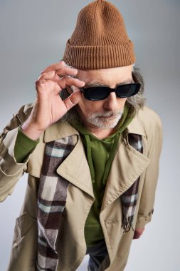 Gri arka plan, hippi modası, bereli şapka, bej palto, ekose atkı, modaya uygun yaşlanma, moda çekimi
