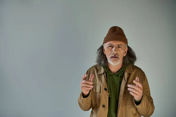 Upset Worried Senior Bearded Man Beanie Hat Brown Jacket Gesturing — Stock Photo, Image