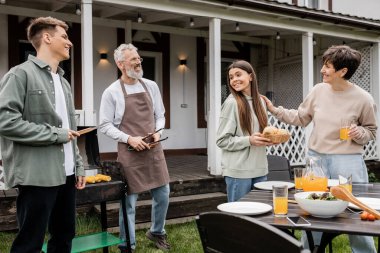Mutlu ebeveynler günü, aile ve yemek, neşeli orta yaşlı ebeveynler, kız ve oğul, yazlık evde aile bbq partisi, banliyö, haftasonu, bağlanma ve modern ebeveynlik, barbekü 