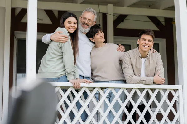 stock image parents day, middle aged parents hugging daughter and young adult son on porch of summer house, family celebration, bonding, modern parenting, moments to remember, reunion 