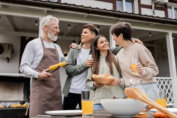 両親の日 お祝い 幸せな中年の両親10代の娘と若い大人の息子とBbqパーティーを持っている父親グリルコーン 夏の家 郊外生活 6月とトンを保持 — ストック写真