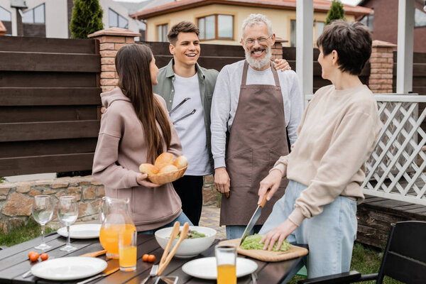 celebration of parents day concept, family photo, excited and happy siblings near middle aged mom and dad, grill party, standing on backyard of summer house, bbq preparations 
