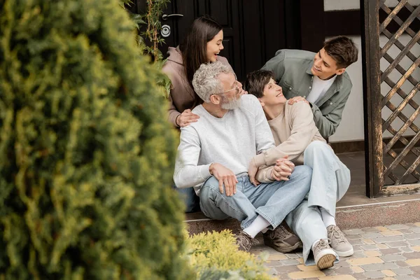Cheerful Kids Hugging Talking Middle Aged Parents While Sitting Together — Stock Photo, Image