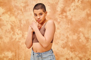 body positivity, sensual and tattooed woman in crop top posing on mottled beige background, looking at camera, representation of body, curvy, different body shapes, generation z, youth  clipart