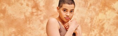 body positivity, sensual and tattooed woman in crop top posing on mottled beige background, looking at camera, representation of body, different body shapes, generation z, youth, banner  clipart