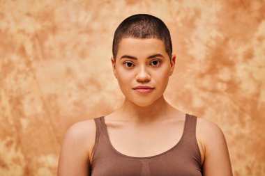 natural look, self-acceptance, young woman with short hair posing on mottled beige background, individuality, looking at camera, generation z, beauty and confidence, body positivity, tattooed  clipart
