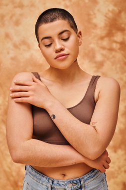 natural look, tattooed young woman with short hair posing on mottled beige background, individuality, modern generation z, beauty and confidence, body positivity movement, youth culture  clipart