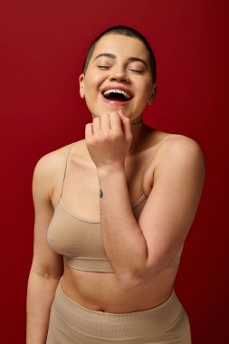 self-esteem, excited and tattooed woman in beige underwear posing on red background, body positivity, curvy fashion, comfortable in skin, self-acceptance, generation z, body diversity, laughter  clipart