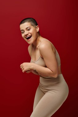 Kendine saygı, mutlu ve dövmeli kadın kırmızı arka planda bej iç çamaşırlı, kıvrımlı moda, ten rengi, vücut pozitifliği, z nesli, vücut çeşitliliği, kahkaha, neşe 