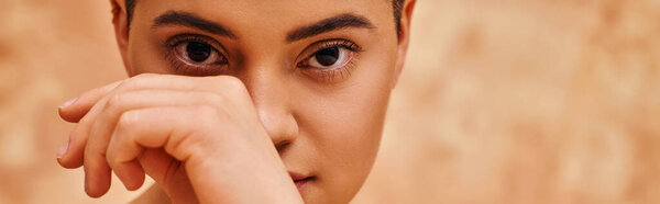 natural look, self-acceptance, young woman with short hair posing on mottled beige background, hand near face, individuality, modern generation z, beauty and skincare, banner  